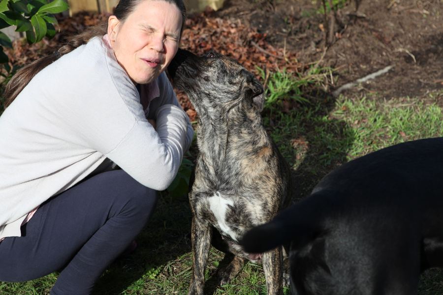 Dog nuzzling a laughing woman's ear