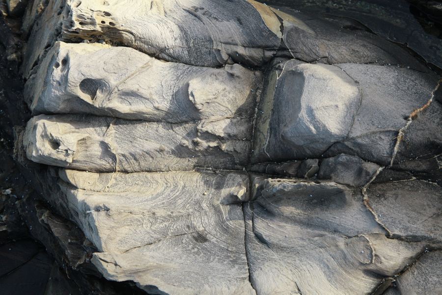 Weathered rock face with swirling grain like currents frozen in stone